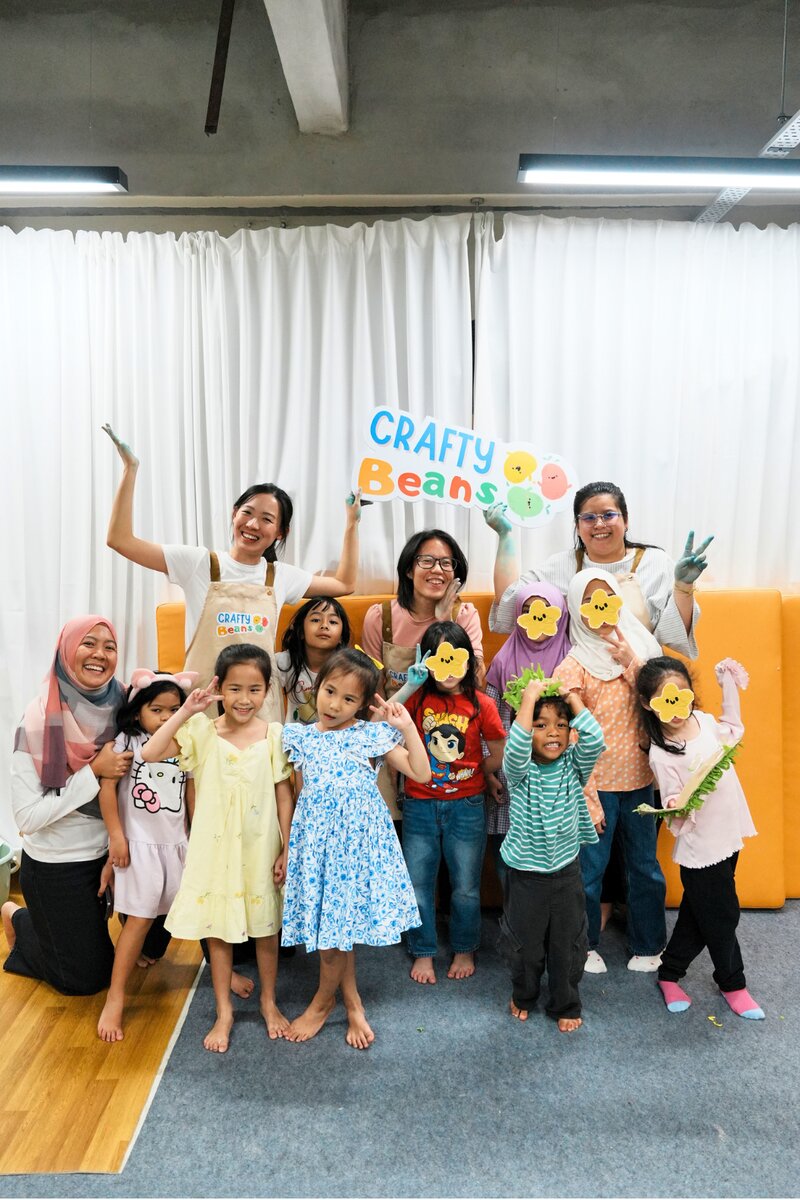 Facilitators and children posing together with the Crafty Beans sign