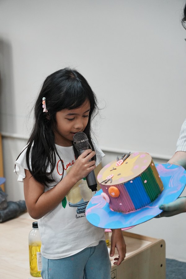 A child sharing her craft into a microphone