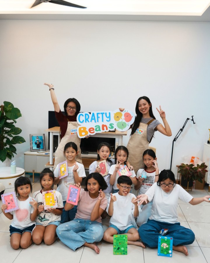 A group of children and facilitators showing off their painted frame crafts