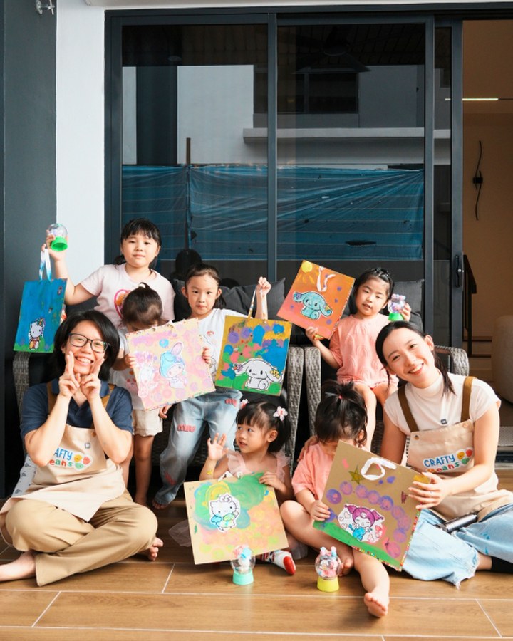 Children showing off their painted canvas totes with facilitators