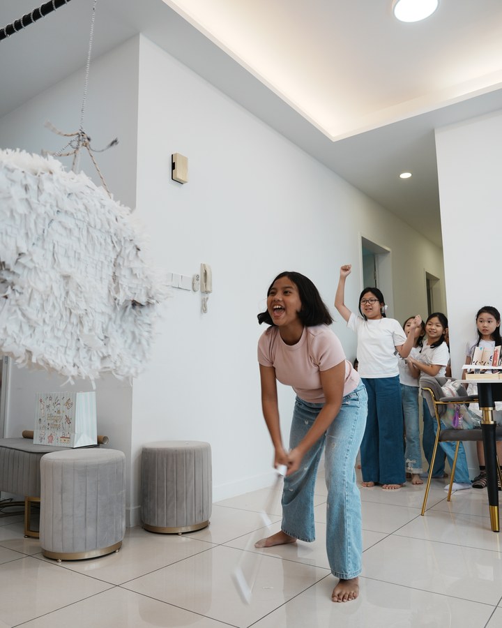 A child swinging at a pinata while others cheer