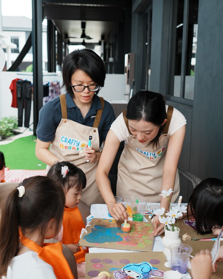 Facilitators helping children with a stamp painting activity