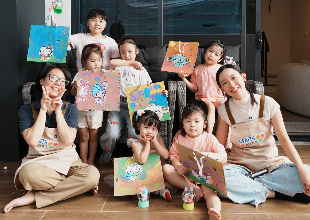 Facilitators and children showing off their painted canvas crafts