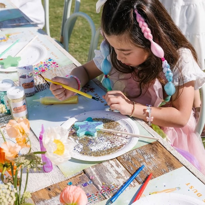 A child decorating a glittery star craft at an outdoor party